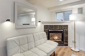 A living room with a white sofa, a fireplace, a mirror, and a floor lamp. - Walkable Green Lake Studio w/ Fireplace (Seattle)