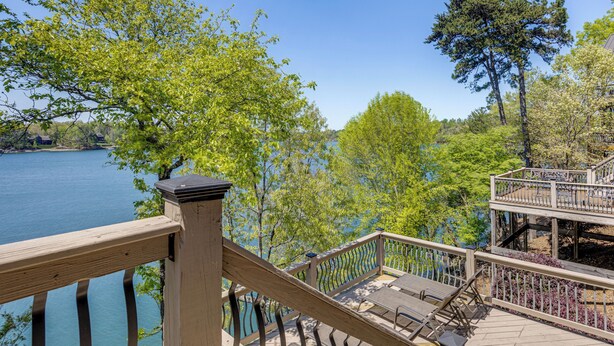 Eine Holzterrasse mit Sitzgelegenheiten im Freien mit Blick auf einen See, umgeben von Bäumen.