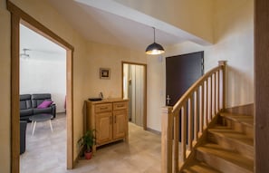 A staircase leading to a second floor, a wooden cabinet, a black sofa, and a potted plant. - Gite Aveyron  l'Orchis 8 pers Bezonnes Bozouls. 4 étoiles 4 épis. (Rodelle)