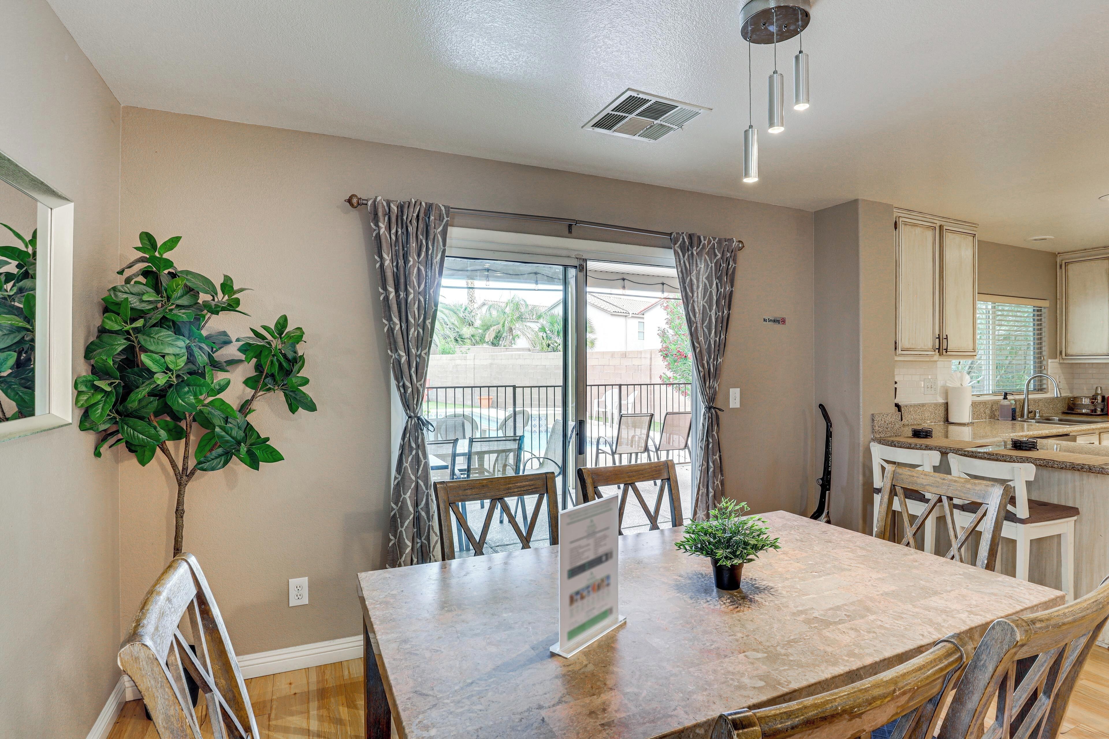 A dining area with a table, chairs, a potted plant, and a view through a window.