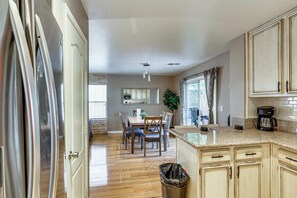 A kitchen with wooden cabinets, a granite countertop, a coffee maker, and a dining area with a table and chairs. - 8 Mi to Strip! Poolside Desert Escape in Las Vegas (Las Vegas)