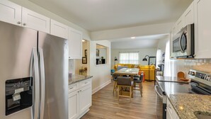 Una cucina moderna con elettrodomestici in acciaio inossidabile, una zona pranzo con sedie gialle e una disposizione luminosa e aperta.