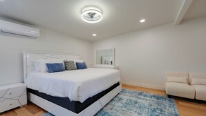 A modern bedroom with a bed, bedside tables, a mirror, and a sofa.