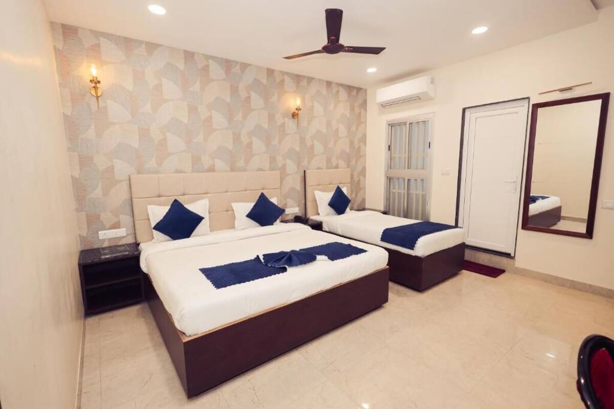 A hotel room with two beds, a ceiling fan, a large mirror, and a window.
