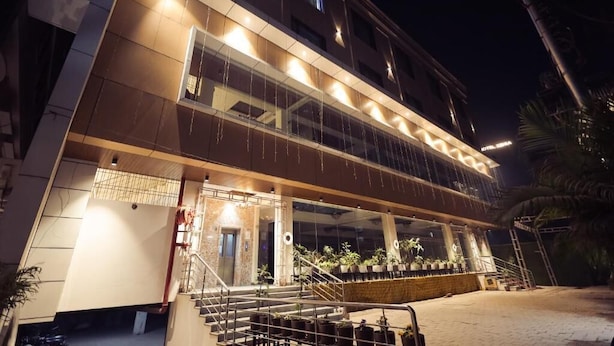 A hotel with a modern design, featuring a prominent staircase, multiple balconies, and a well-lit entrance. - HOTEL VANSHI VAT (Varanasi)
