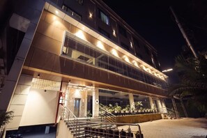 A hotel with a modern design, featuring a prominent staircase, multiple balconies, and a well-lit entrance. - HOTEL VANSHI VAT (Varanasi)