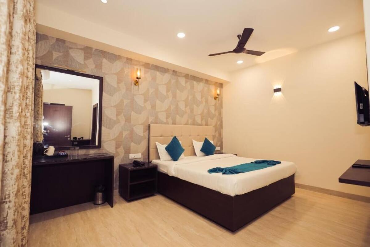 A bedroom with a bed, bedside table, mirror, and ceiling fan.