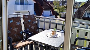 Een terras met een tafel, stoelen en uitzicht op omliggende huizen.