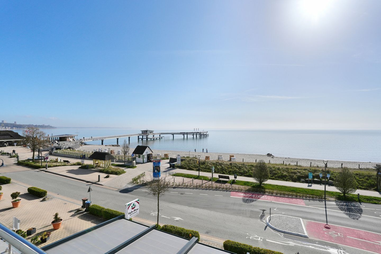 Une vue sur la côte avec une jetée, une plage et une route dotée d’une piste cyclable.