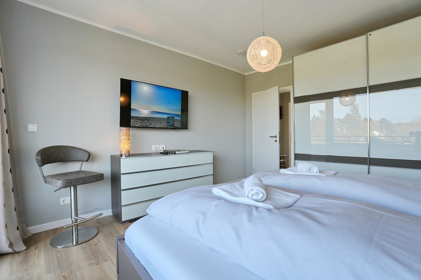 Habitación de hotel moderna con cama, escritorio, silla, televisor y vista al exterior.
