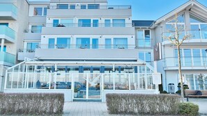 Um hotel moderno com fachada de vidro, várias varandas e entrada central.