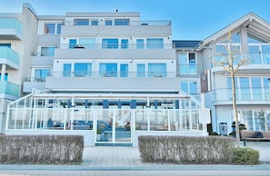 Ein modernes Hotel mit Glasfassade, mehreren Balkonen und einem zentralen Eingang.