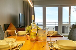 Ein Esstisch, gedeckt mit Tellern, Besteck, einer Weinflasche, einem Glas und einer Willkommenskarte.