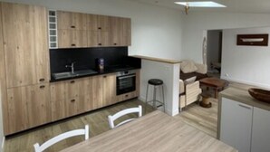 A modern kitchen with wooden cabinets, a dining table, and a small island with stools.
