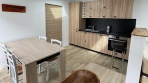 A modern kitchen with wooden cabinets, a dining table, and a built-in oven.