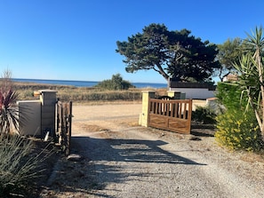 Un camino de grava conduce a una entrada portonada, con vista al mar.