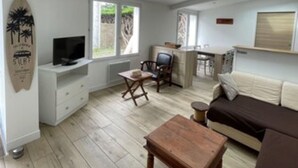 A living room with a sofa, a TV, a wooden coffee table, a chair, and a small table.