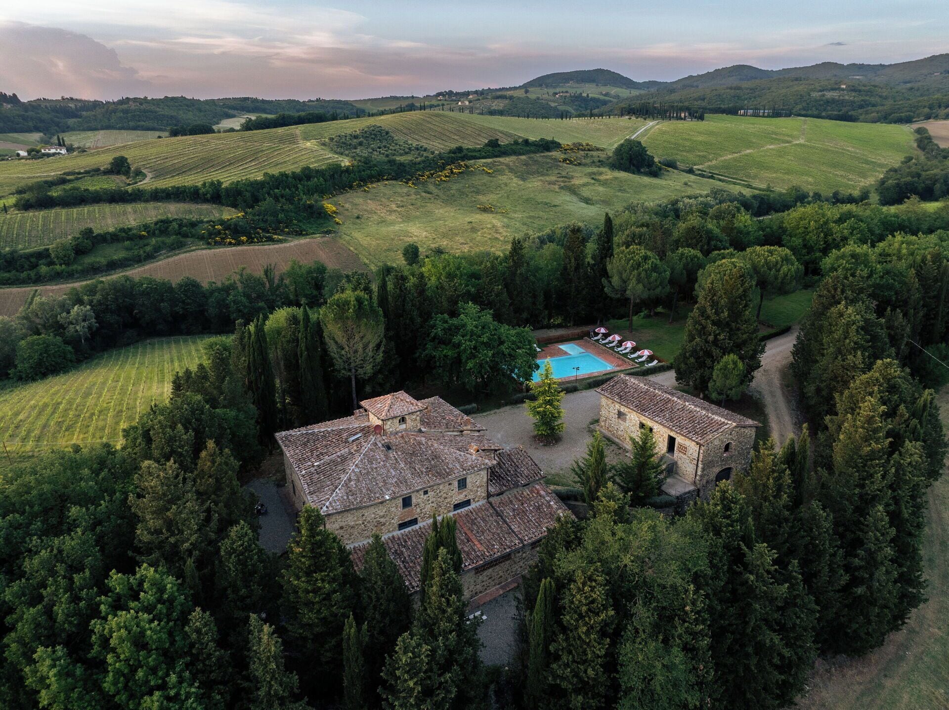 A rural property with stone buildings, a swimming pool, and surrounding fields.