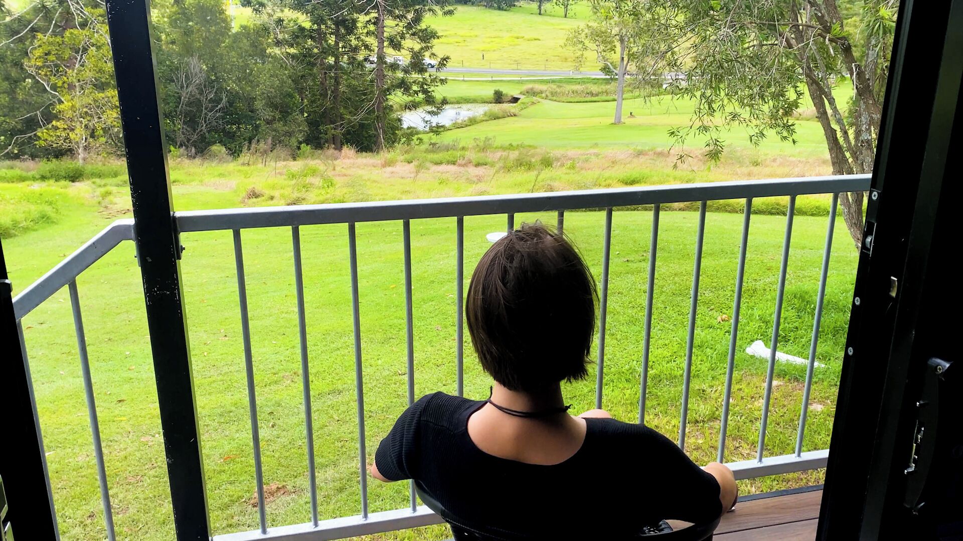 Varanda com vista para uma paisagem verde, incluindo um campo de golfe.