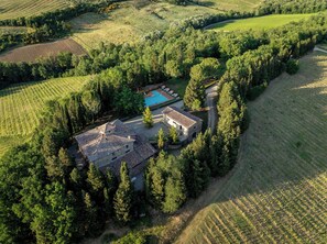 Luftaufnahme eines Anwesens mit einem Steinhaus, einem Schwimmbad und umliegenden Feldern.