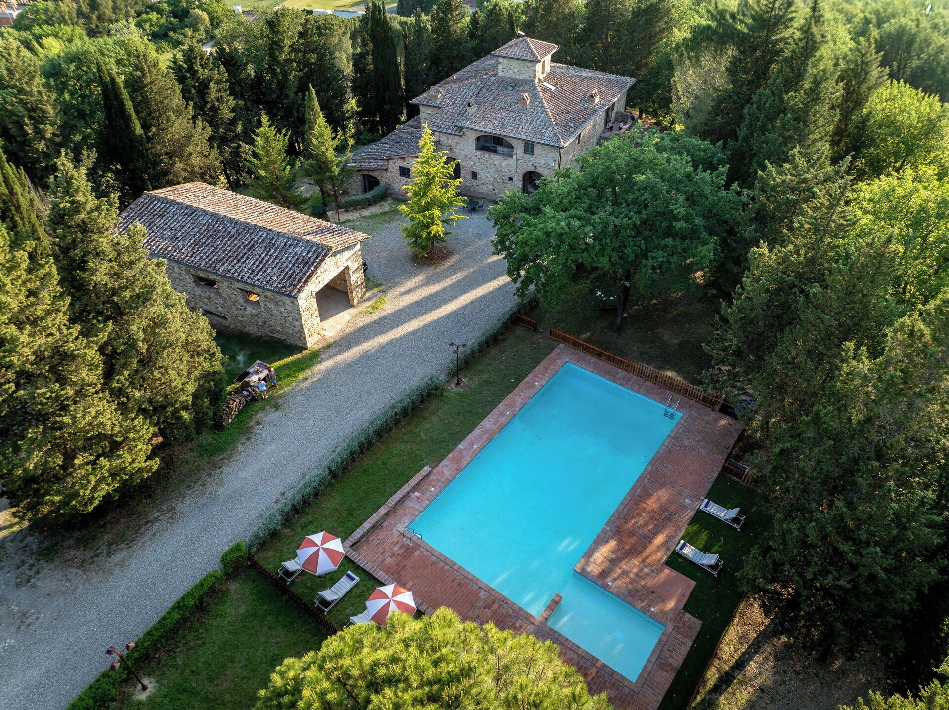 A stone building with a swimming pool, surrounded by trees.
