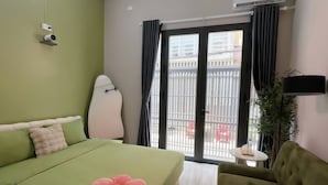A room with a bed, a green sofa, a small table, and a view through a window. - Trisstay Saigon - Dien Bien Phu (Ho Chi Minh City)