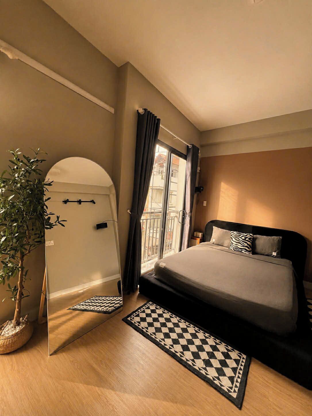 Una camera da letto con un letto, una pianta in vaso, un tappeto a scacchi e vista all'esterno.