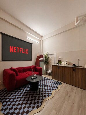 Un salon moderne avec un canapé rouge, une table basse et un grand écran affichant le logo « NETFLIX ».