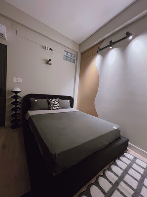 Quarto com cama, luminária, ar-condicionado fixado na parede e luminária de teto.