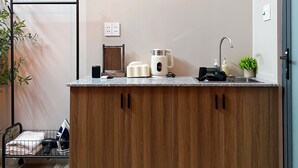 A modern kitchen with a wooden cabinet, a kettle, a toaster, and a sink. There are three artworks on the wall above the counter. - Trisstay Saigon - Dien Bien Phu (Ho Chi Minh City)