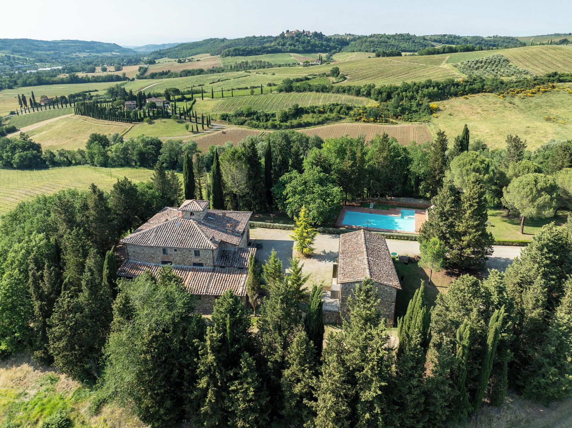 Una villa de piedra con piscina rodeada de árboles, ubicada en un paisaje montañoso.
