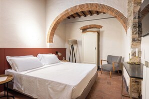 Ein Schlafzimmer mit einem Bett, einem Sessel, einer Lampe und einem rundbogigen Durchgang.