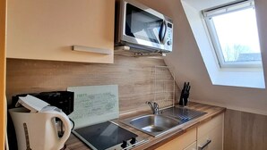 A kitchenette with a microwave, sink, and a window. - Appartmenthaus Nolting Apartment 3 Nolting: 40 m² with terrace and WLAN - (Werdum)