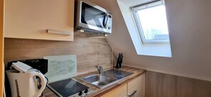 Eine Küchenzeile mit einer Mikrowelle, einem Spülbecken und einem Fenster.