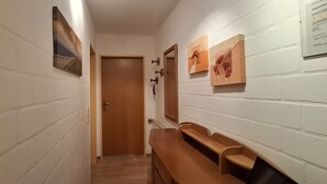 A hallway with white brick walls, wooden benches, and a door at the end. - Appartmenthaus Nolting Apartment 3 Nolting: 40 m² with terrace and WLAN - (Werdum)
