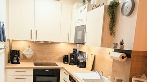 A modern kitchen with white cabinets, a built-in oven, a coffee maker, and a sink. - Vacation home Am Kurzentrum 26 No. 3 (Wittmund)