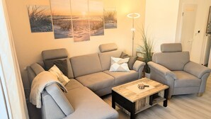 A modern living room with a sofa, two armchairs, a coffee table, and wall art. - Vacation home Am Kurzentrum 26 No. 3 (Wittmund)