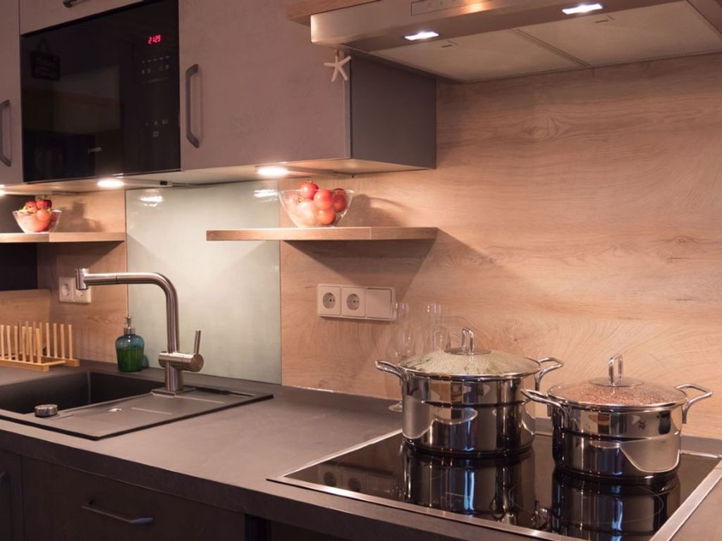A modern kitchen with a built-in microwave, stainless steel sink, and a stove top.
