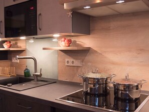 Een moderne keuken met een ingebouwde magnetron, een RVS-spoelbak en een kookplaat.