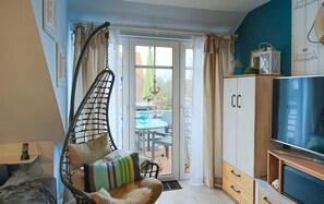 Een kamer met een hangstoel, een televisie, een kledingkast en uitzicht op het buitenterras.