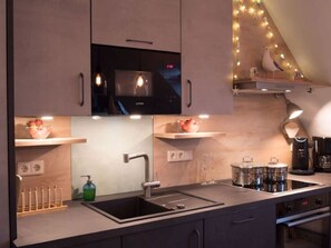 Een moderne keuken met een ingebouwde magnetron, een spoelbak en een koffiezetapparaat.