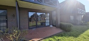 Ein modernes Haus mit Ziegelaußenwand, großen Glasüren und einer gepflasterten Terrasse.