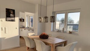 Une cuisine moderne avec des meubles blancs, une table à manger en bois et une fenêtre offrant une belle vue.