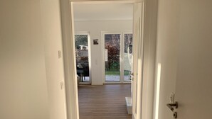 Un couloir au plancher de bois menant à une porte en verre.