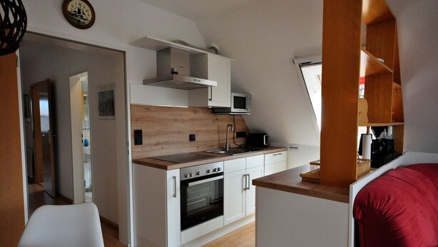 A compact kitchen with a microwave, stove, and oven, wooden countertops, and white cabinetry. - Wohnpark Legewarfen 2/3 - Holiday apartment Wohnpark Legewarfen 2/2 (Werdum)