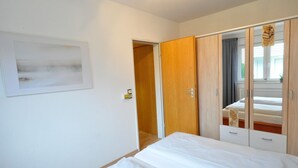 Une chambre à coucher comprenant un lit, une armoire et une porte donnant sur une autre pièce.