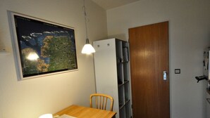 Une cuisine de taille réduite avec une table en bois, un luminaire suspendu, un réfrigérateur et une carte accrochée au mur.