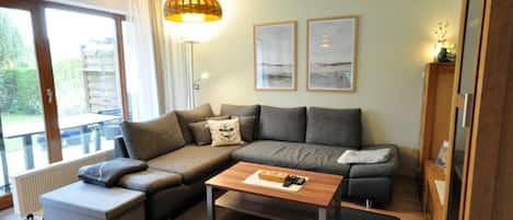 A modern living room with a sectional sofa, a coffee table, and a large window offering a view of the outdoors.