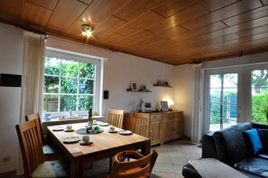 A dining area with a wooden table, chairs, and a sofa. - Vacation home Uferstraße 2 F - Holiday home Uferglück Uferstraße 2 F (Wittmund)