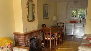 Een woonkamer met een open haard, een eettafel en een keukenhoek.